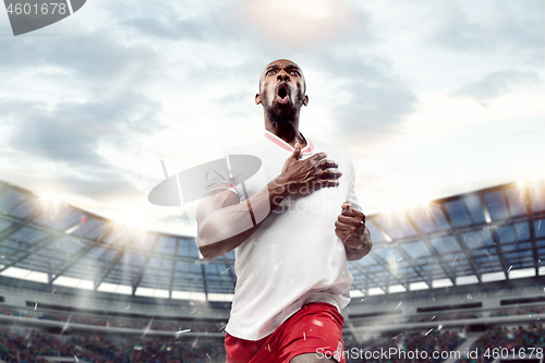 Image of The football player in motion on the field of stadium