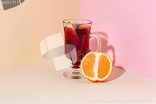 Image of Mulled wine in glass with cinnamon stick, christmas sweets on on the glass table