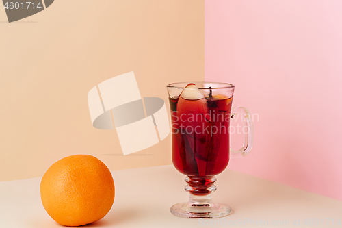 Image of Mulled wine in glass with cinnamon stick, christmas sweets on on the glass table