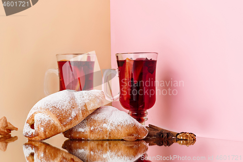 Image of Mulled wine in glass with cinnamon stick, christmas cake on on the glass table