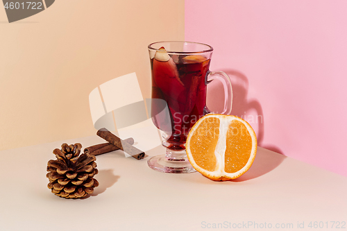 Image of Mulled wine in glass with cinnamon stick, christmas sweets on on the glass table