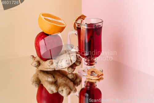 Image of Mulled wine in glass with cinnamon stick, christmas sweets on on the glass table