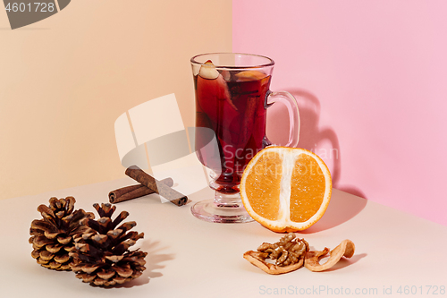 Image of Mulled wine in glass with cinnamon stick, christmas sweets on on the glass table