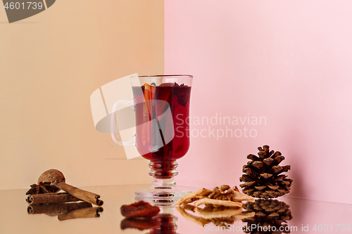 Image of Mulled wine in glass with cinnamon stick, christmas sweets on on the glass table