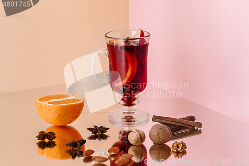 Image of Mulled wine in glass with cinnamon stick, christmas sweets on on the glass table