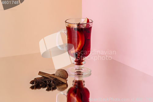 Image of Mulled wine in glass with cinnamon stick, christmas sweets on on the glass table