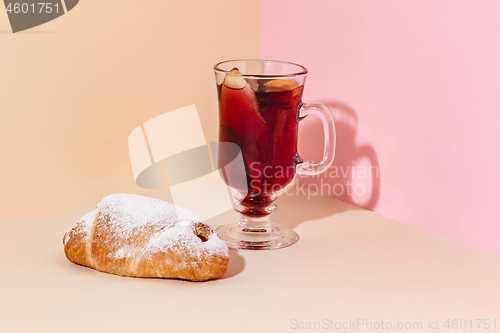 Image of Mulled wine in glass with cinnamon stick, christmas cake on on the glass table