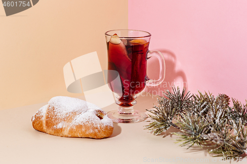 Image of Mulled wine in glass with cinnamon stick, christmas cake on on the glass table
