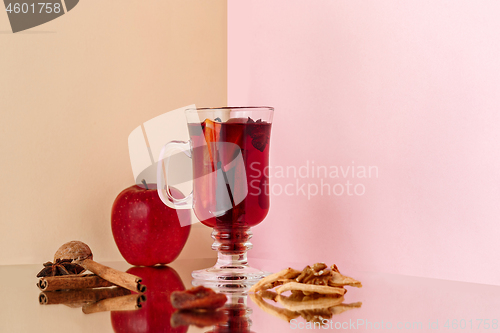 Image of Mulled wine in glass with cinnamon stick, christmas sweets on on the glass table