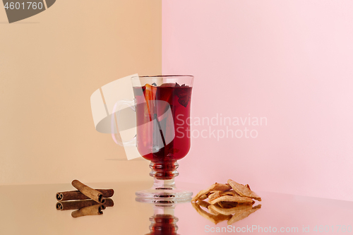 Image of Mulled wine in glass with cinnamon stick, christmas sweets on on the glass table
