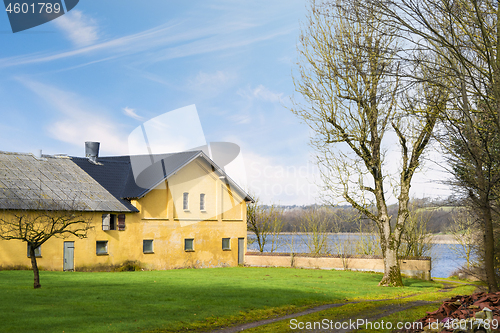 Image of Yellow farm house by a lake in the spring