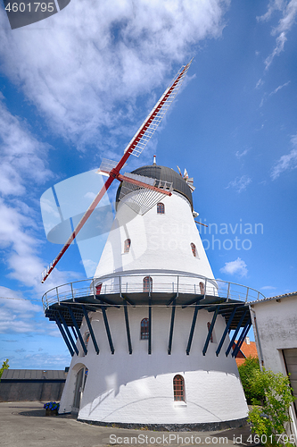 Image of Old windmill rising up to a blue sky