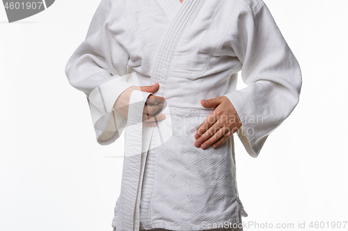 Image of Stages of correct tying of the belt by a teenager on a sports kimono, step two