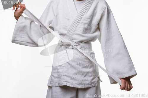 Image of Stages of correct tying of the belt by a teenager on a sports kimono, step nine