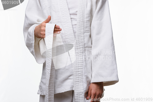 Image of Stages of correct tying of the belt by a teenager on a sports kimono, step one