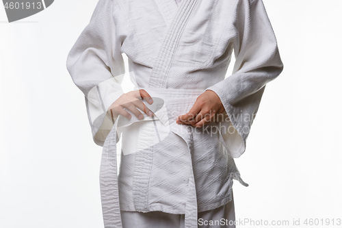 Image of Stages of correct tying of the belt by a teenager on a sports kimono, step five