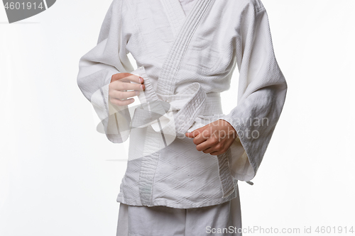 Image of Stages of correct tying of the belt by a teenager on a sports kimono, step eight