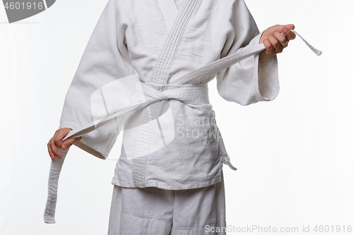 Image of Stages of correct tying of the belt by a teenager on a sports kimono, step seven