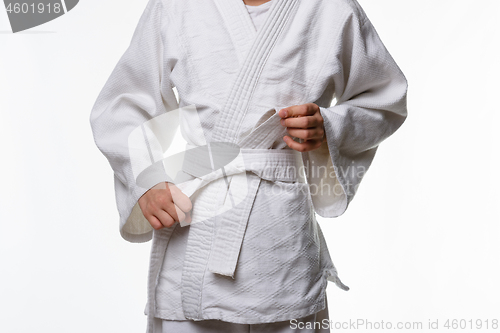 Image of Stages of correct tying of the belt by a teenager on a sports kimono, step six