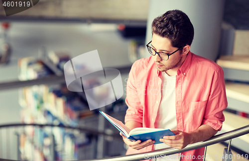 Image of student boy or young man reading book at library