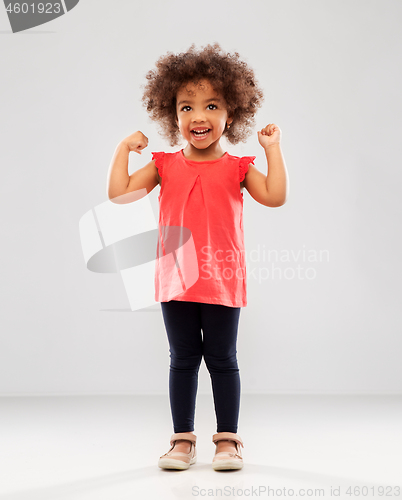 Image of happy little african american girl showing power