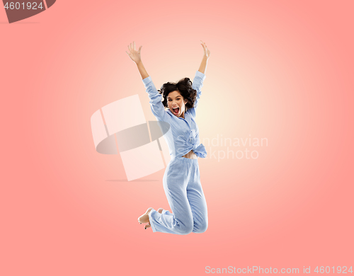 Image of happy woman in blue pajama jumping high over pink