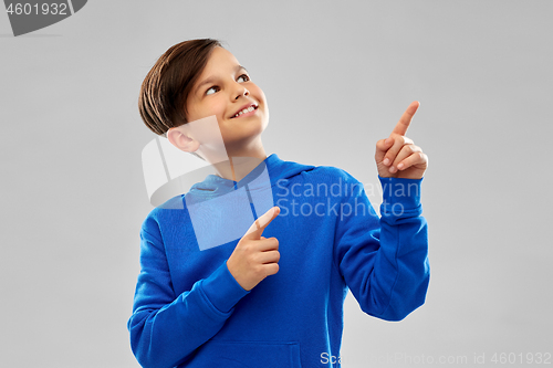 Image of happy boy in blue hoodie pointing fingers upwards