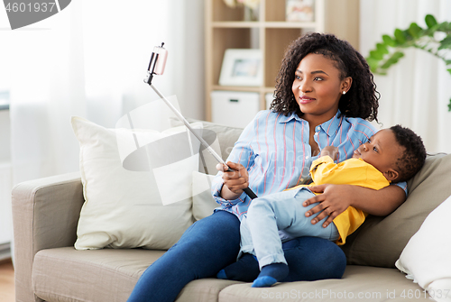 Image of african mother with baby son taking selfie at home