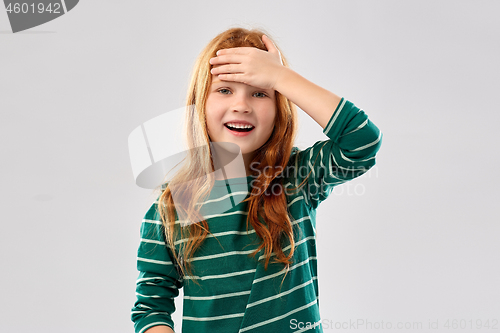 Image of smiling red haired girl holding to her head