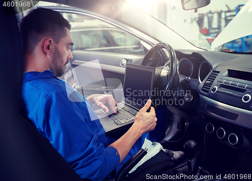 Image of mechanic man with laptop making car diagnostic