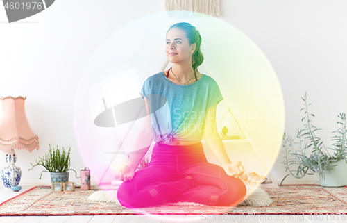 Image of woman meditating in lotus pose at yoga studio