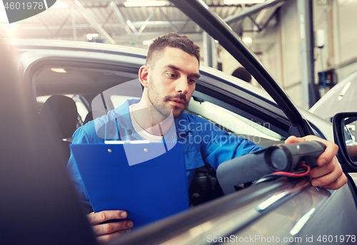 Image of mechanic man with diagnostic scanner at car shop