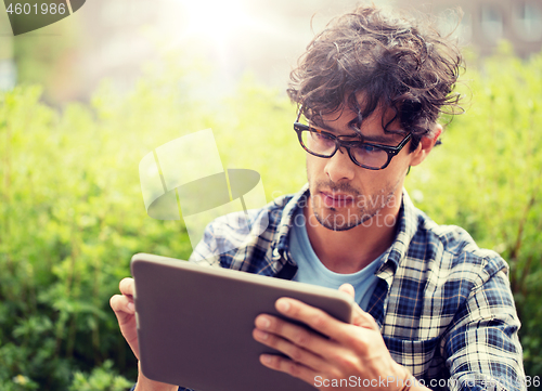 Image of man in glasses with tablet pc computer outdoors