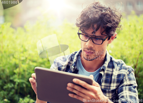 Image of man in glasses with tablet pc computer outdoors