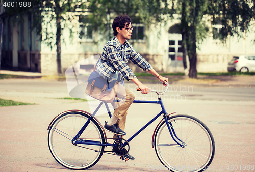 Image of young hipster man with bag riding fixed gear bike