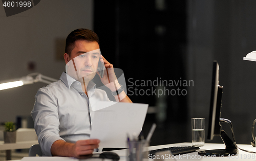 Image of businessman calling on sartphone at night office