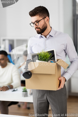 Image of sad fired male office worker with personal stuff