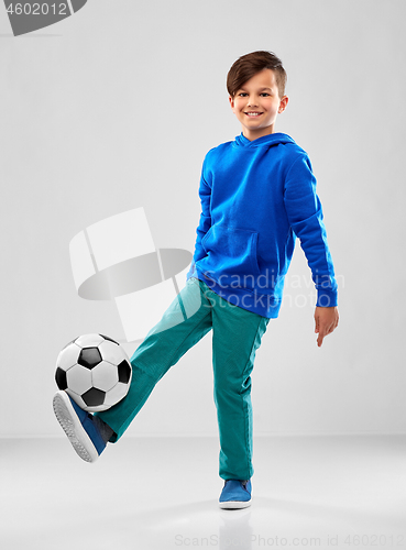 Image of smiling boy in blue hoodie playing soccer ball