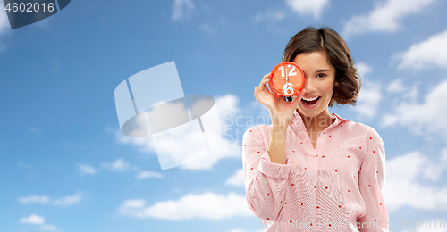 Image of happy young woman in pajama with alarm clock