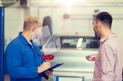 Image of auto mechanic with clipboard and man at car shop