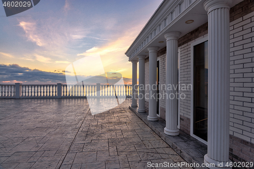 Image of Beautiful building with columns on a landscaped promenade at sunset