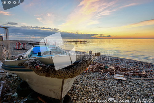 Image of An old boat on the beach against the backdrop of a beautiful sea sunset