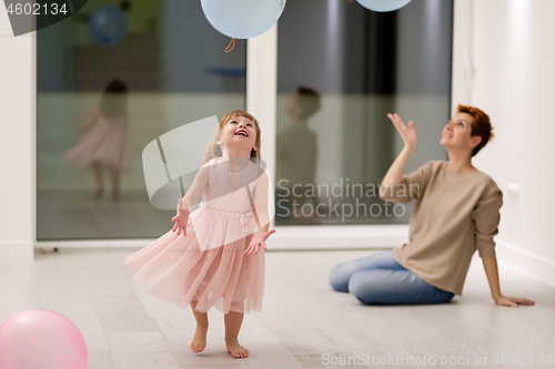 Image of mother and cute little daughter playing with balloons