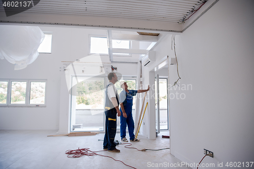 Image of carpenters installing glass door with a wooden frame