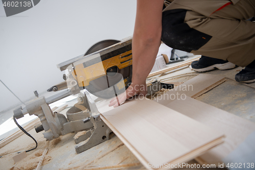 Image of Man cutting laminate floor plank with electrical circular saw