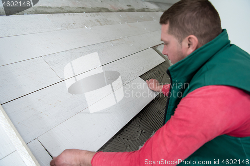 Image of worker installing the ceramic wood effect tiles on the floor