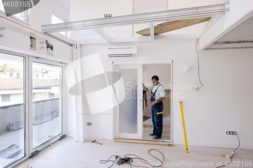 Image of carpenters installing glass door with a wooden frame