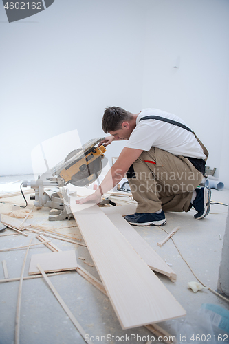 Image of Man cutting laminate floor plank with electrical circular saw