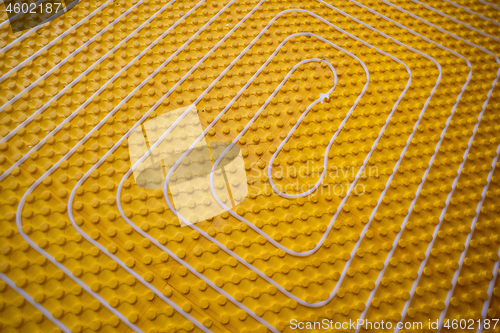 Image of yellow underfloor heating installation with white pipes