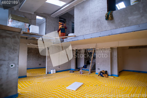 Image of yellow underfloor heating installation with white pipes